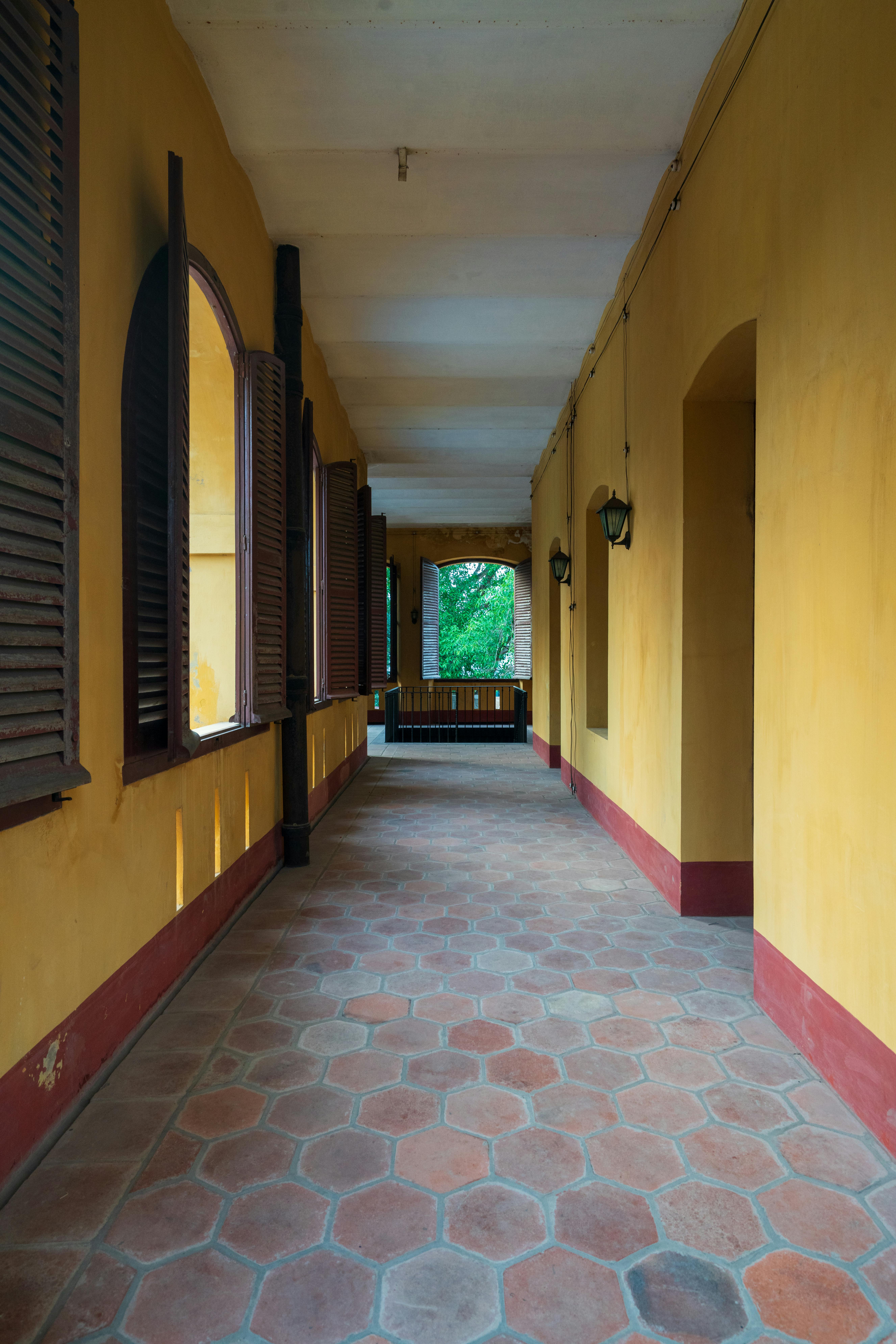 Free Long colonial corridor with wooden shutters and checkerboard tiles, embodying classic architecture. Stock Photo
