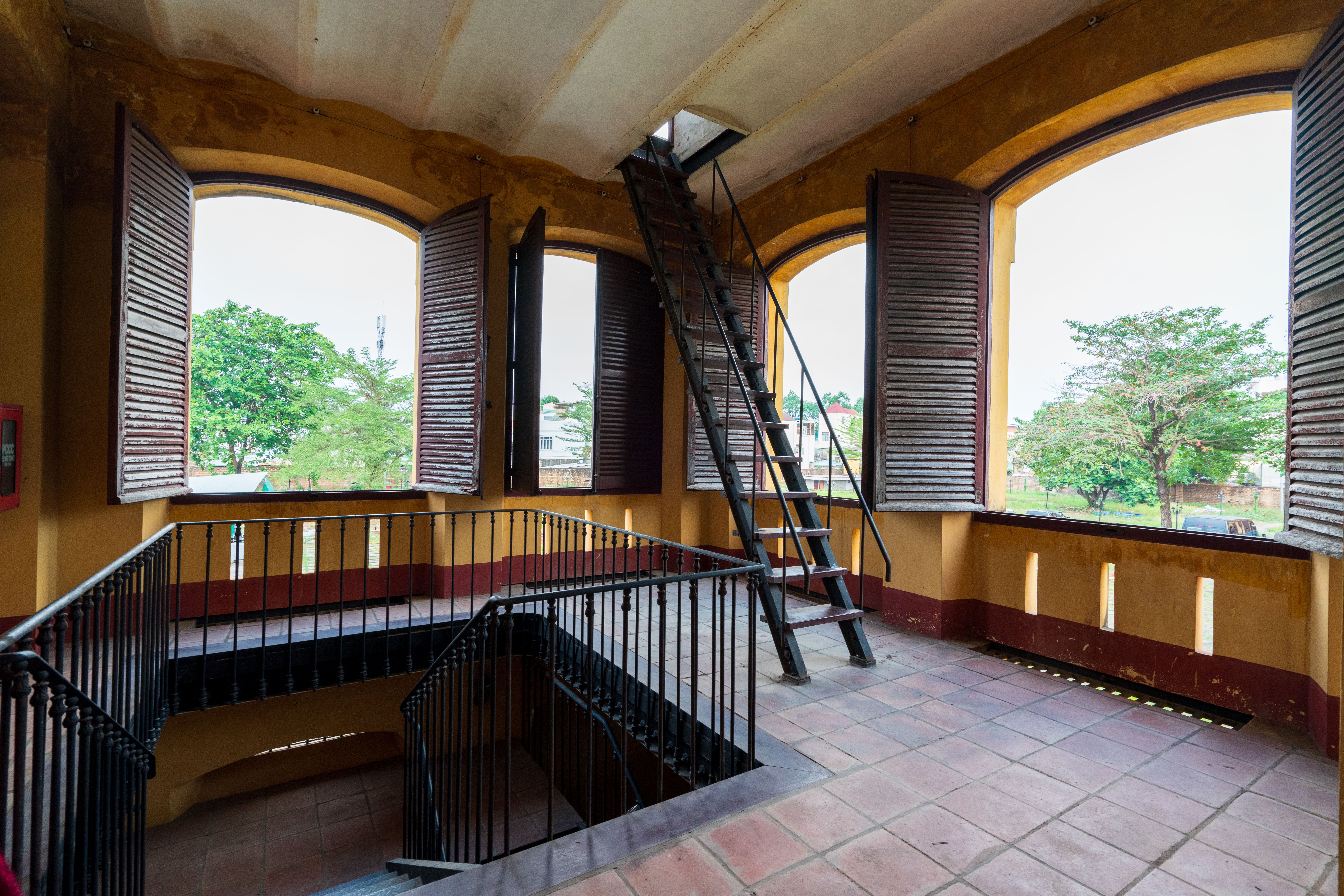 Gratis Interno rustico di un edificio storico con persiane in legno e una scala in metallo che conduce alla soffitta. Foto a disposizione