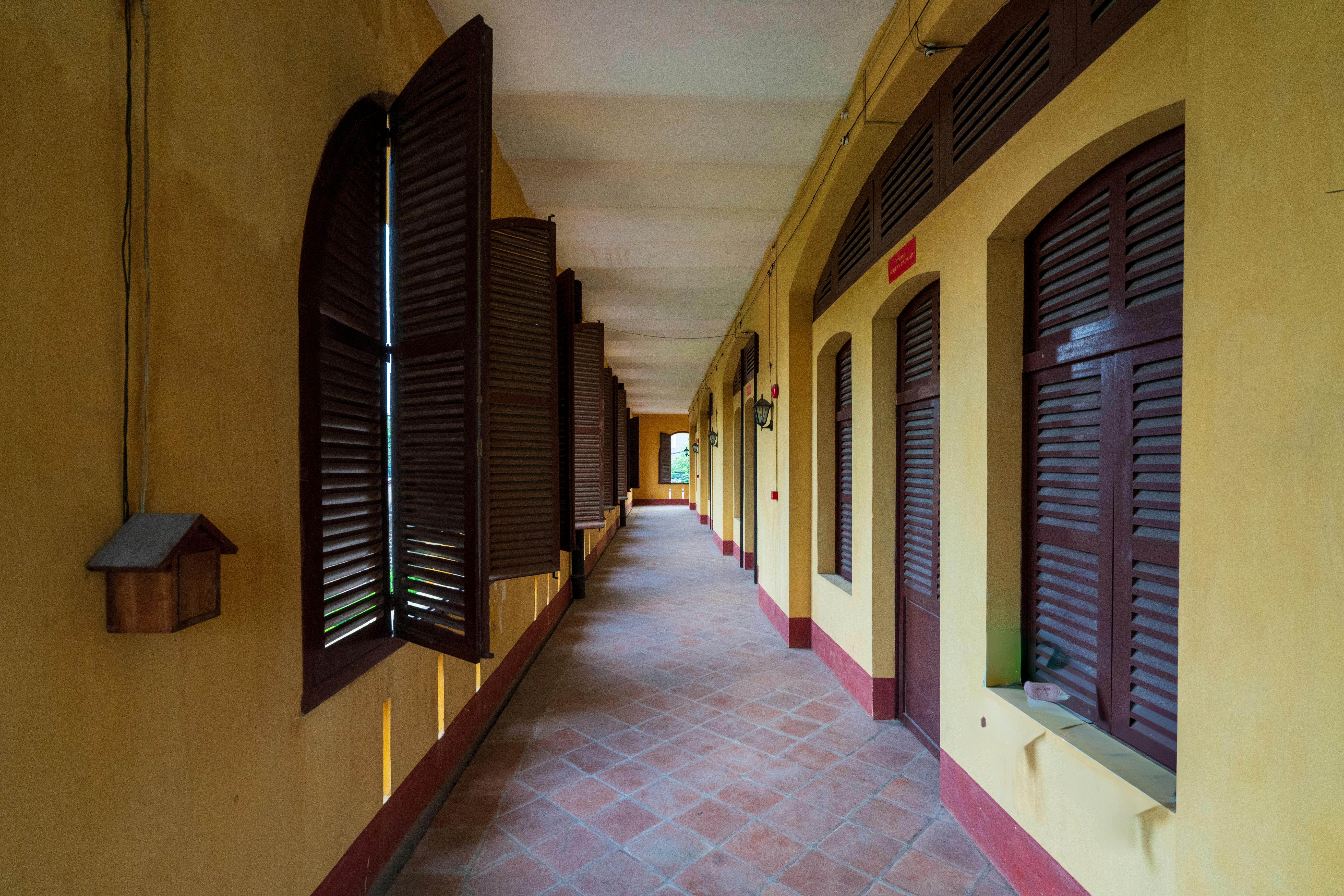 Kostenlos Ein charmanter Korridor im Kolonialstil mit offenen Holzfensterläden und warmen Farben, ideal für architektonische Gestaltungskonzepte. Stock-Foto