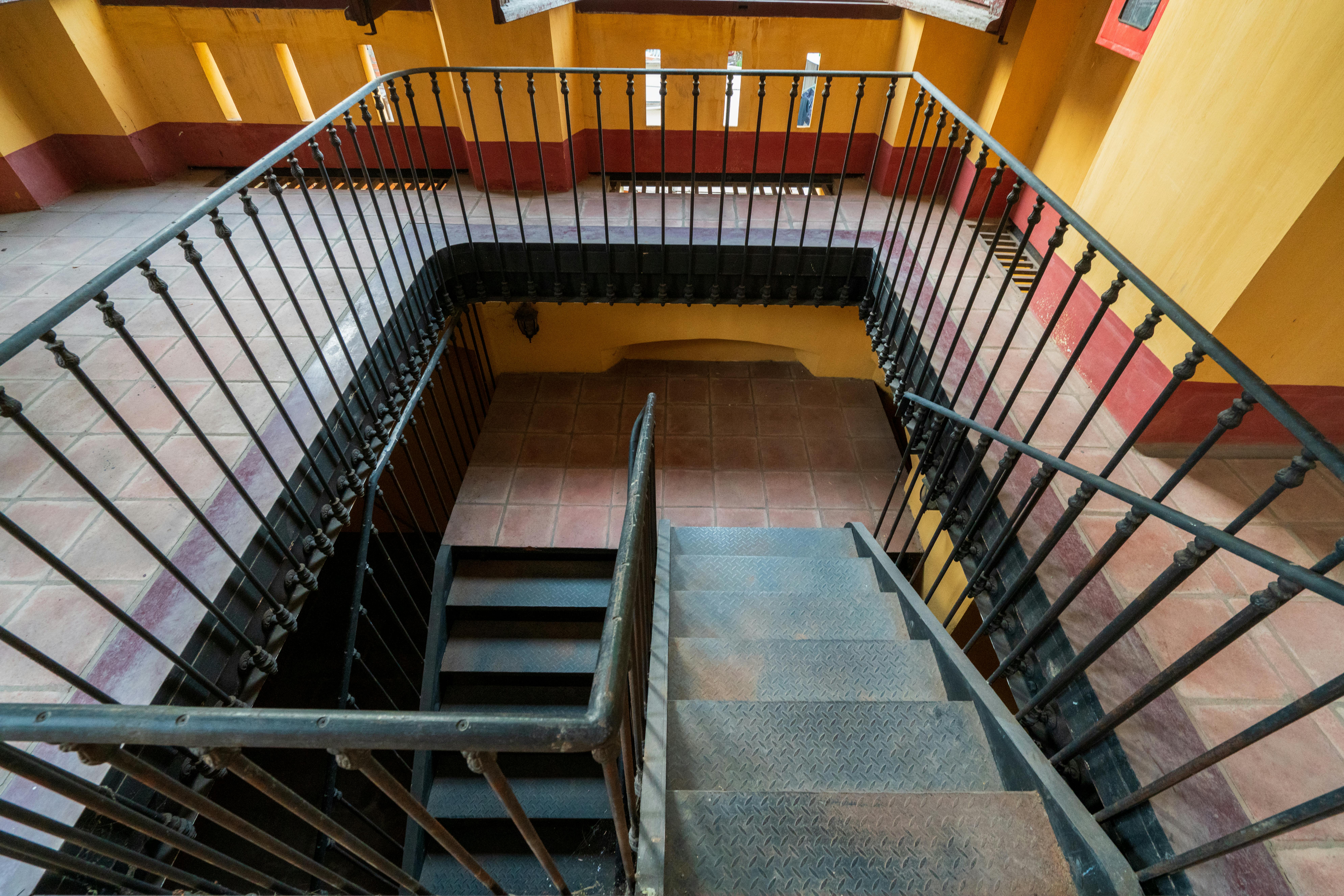 Bezpłatne Intrygujące spiralne schody z metalowymi poręczami w kolorowym, zabytkowym wnętrzu budynku. Zdjęcie z galerii