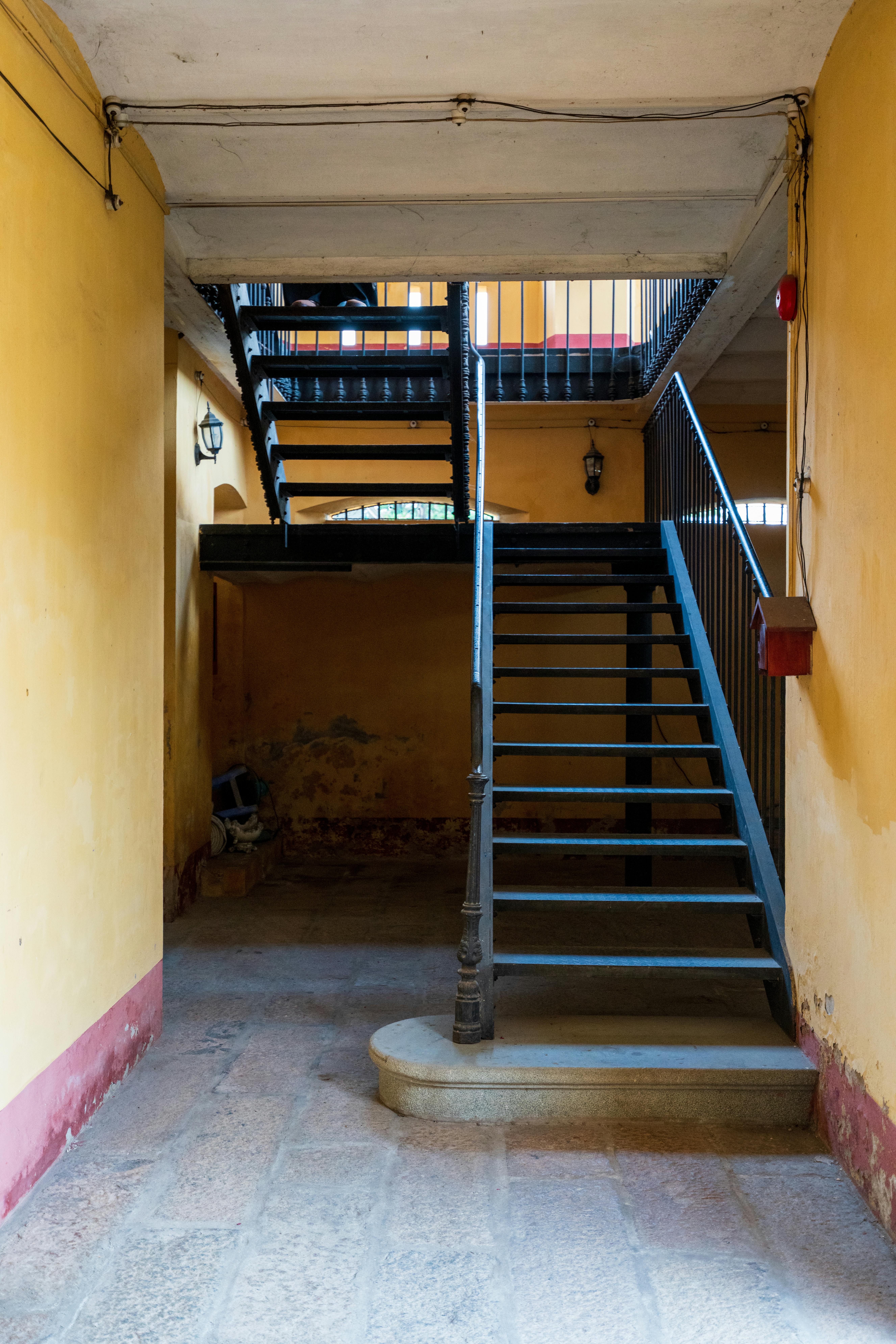 Zadarmo Klasické interiérové ​​schodisko so žiarivými žltými stenami a rustikálnym kovovým zábradlím. Fotka z fotobanky