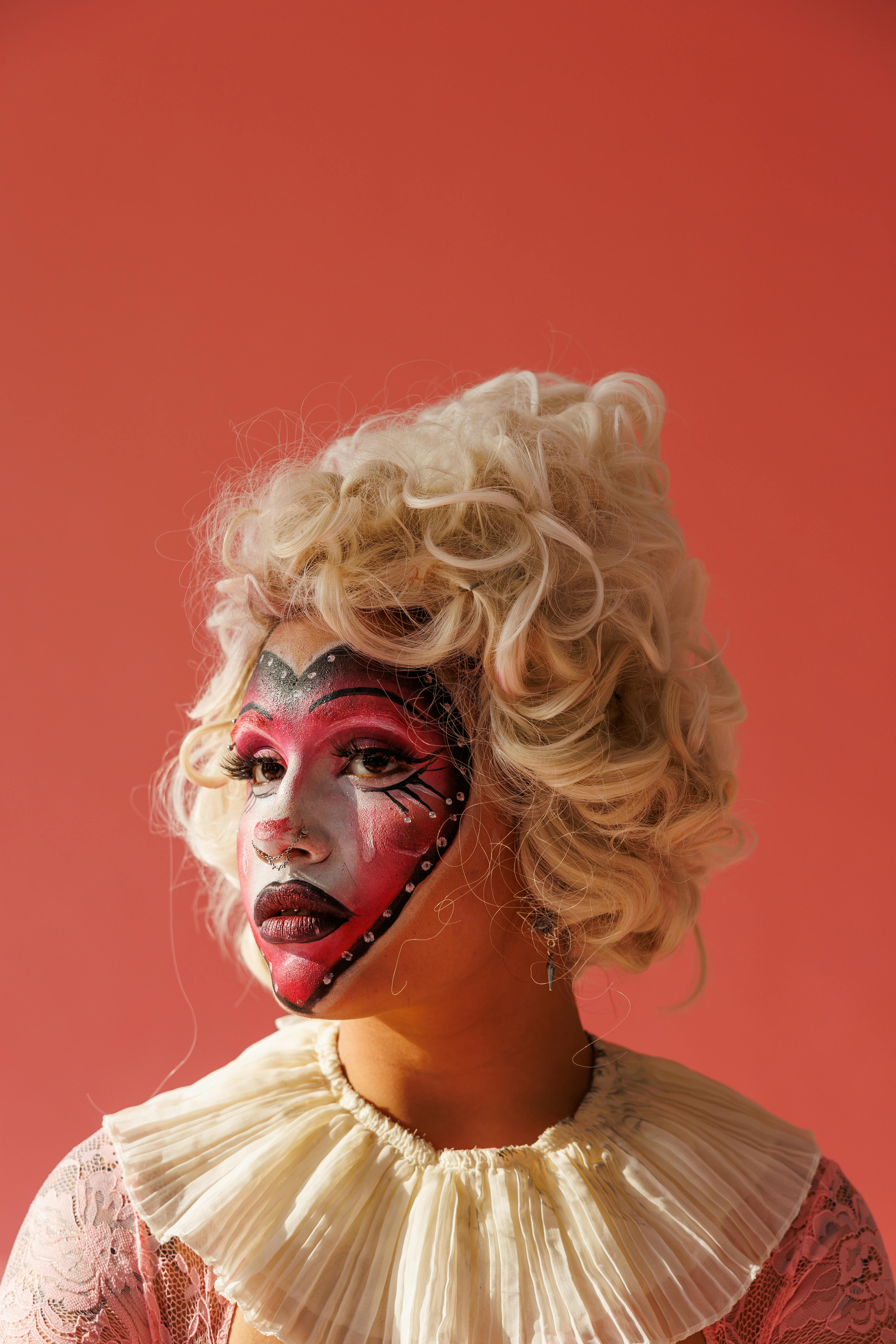 A striking theatrical portrait featuring dramatic face paint and a curly blonde wig, perfect for creative projects.