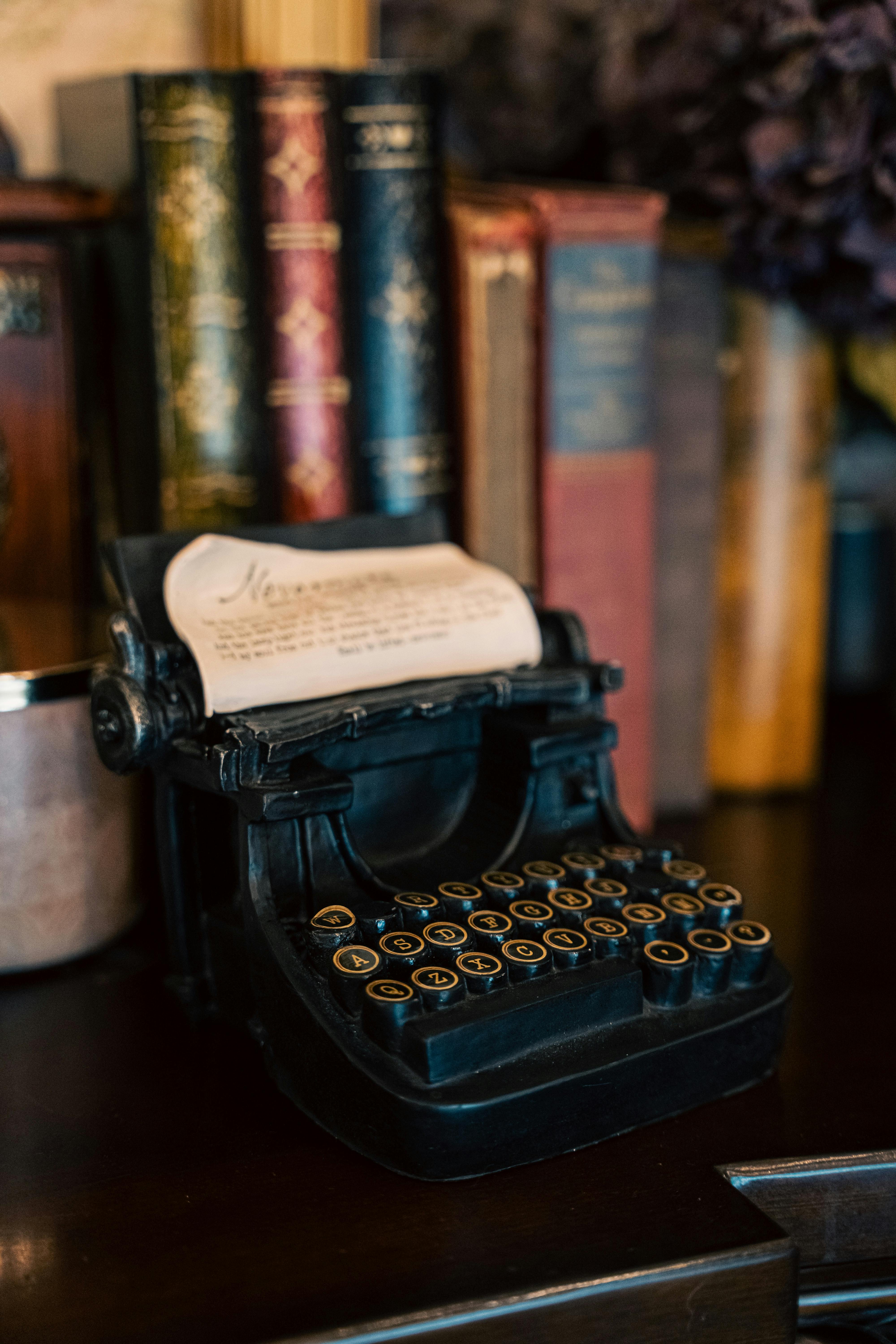 Bezpłatne Klasyczna, zabytkowa maszyna do pisania z rolką papieru stoi wśród starych książek na ciemnej drewnianej półce. Zdjęcie z galerii