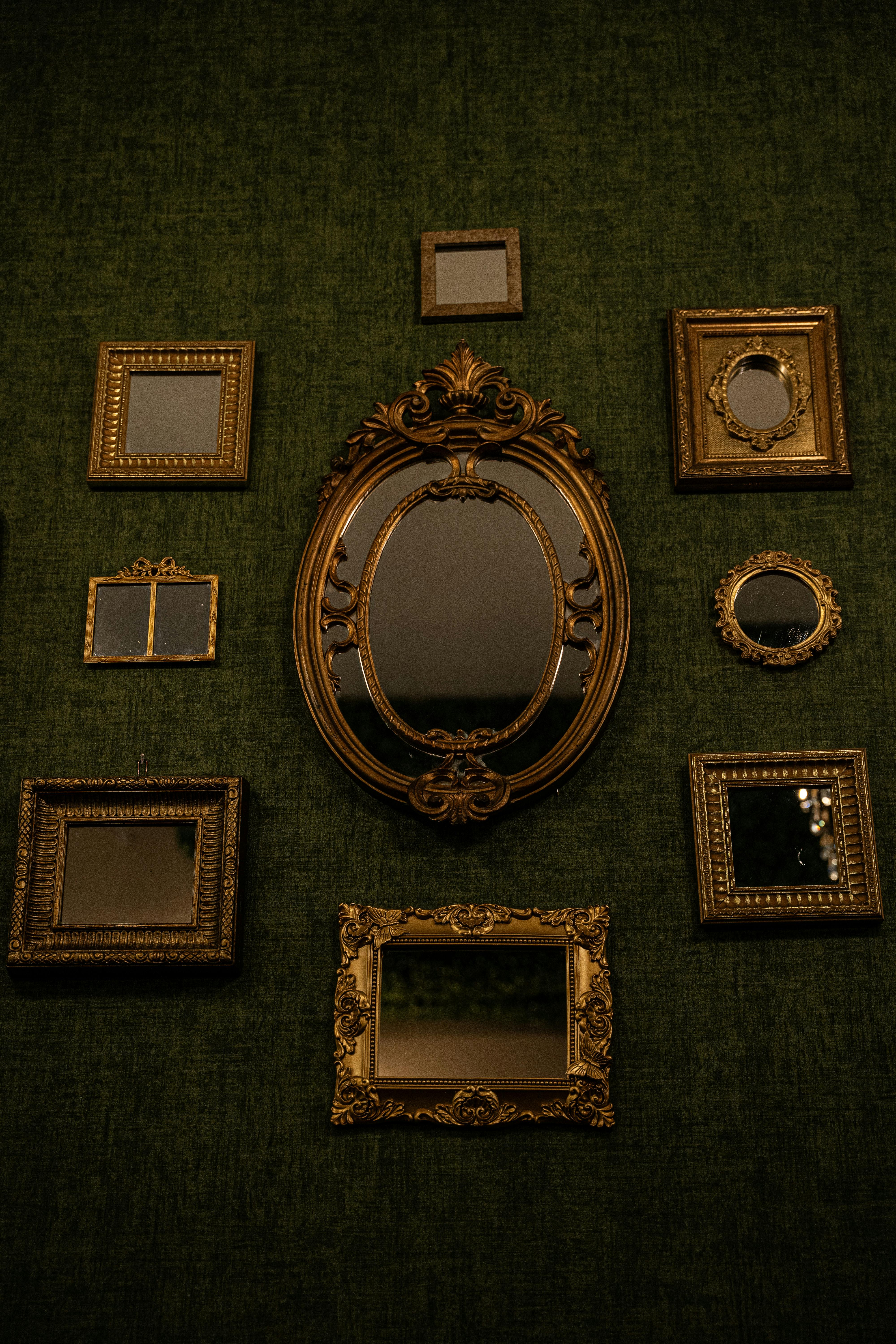 Miễn phí Bộ sưu tập gương cổ trang trí cầu kỳ trên bức tường màu xanh lá cây sần sùi tạo nên vẻ thanh lịch cổ điển. Ảnh lưu trữ