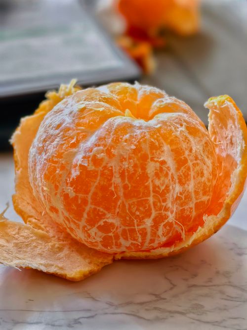 Free Close-up of a peeled orange on a marble surface, highlighting texture and freshness. Stock Photo