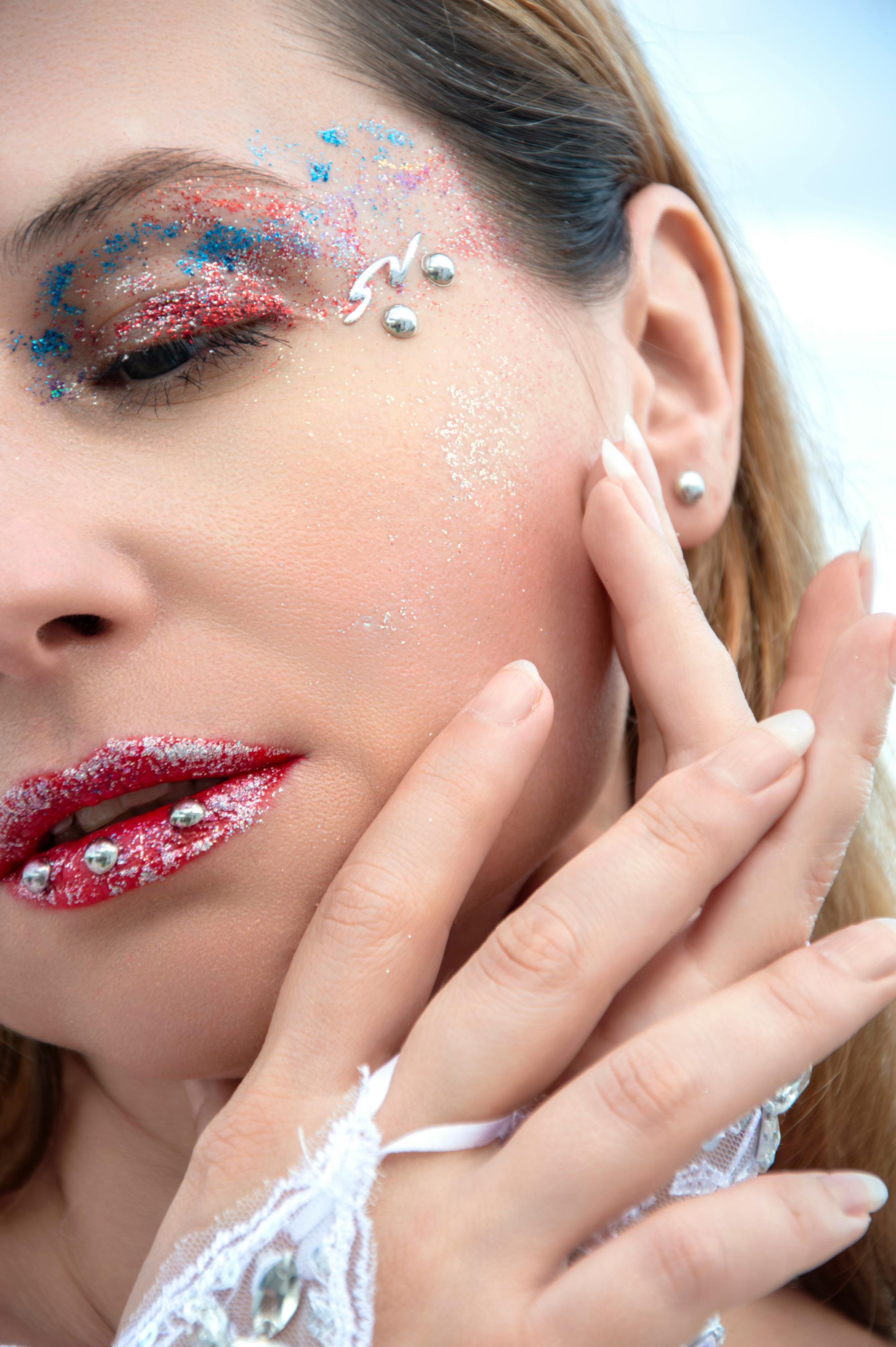 Free Artistic close-up showing glittery makeup with bold red and blue tones on a woman's face. Stock Photo