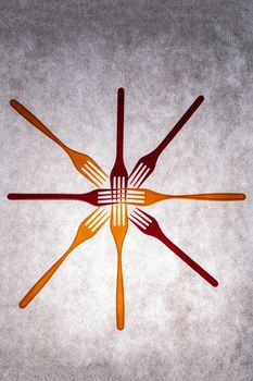 Colorful forks arranged in a starburst pattern on a textured surface.