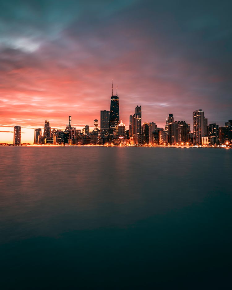 City Skyline Across Body Of Water During Night Time