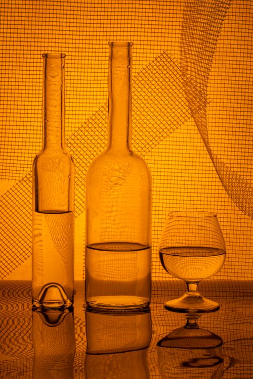Free Elegant arrangement of glass bottles and a glass with abstract lighting. Stock Photo
