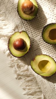 Sliced avocados on textured cloth with natural light and shadows creating a vibrant effect.
