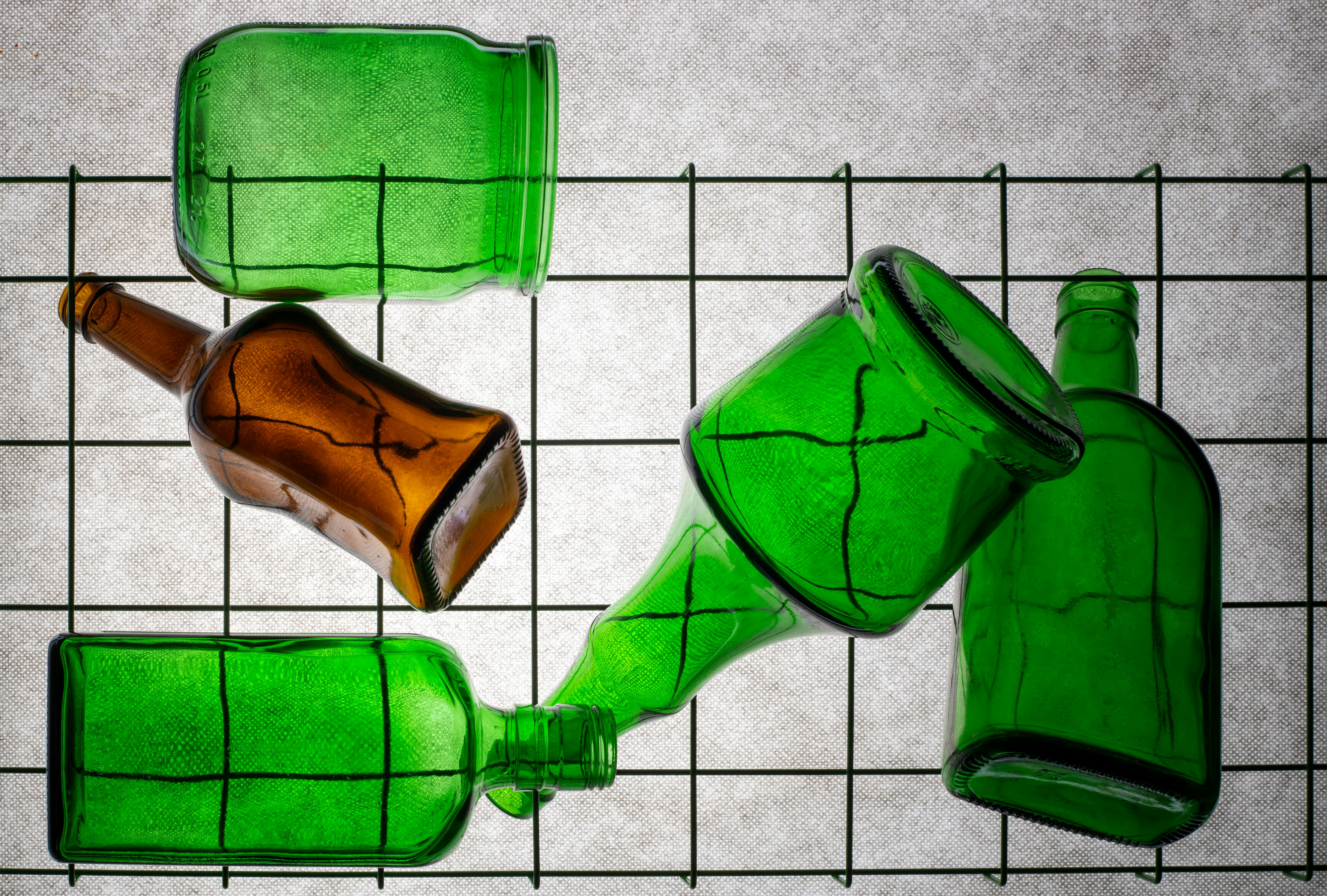 Gratis Disposición artística de botellas de vidrio verdes y marrones sobre un fondo con patrón de cuadrícula. Foto de stock