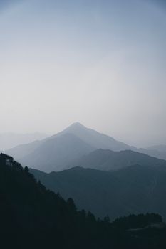 A peaceful view of misty mountains with layered peaks on a calm morning