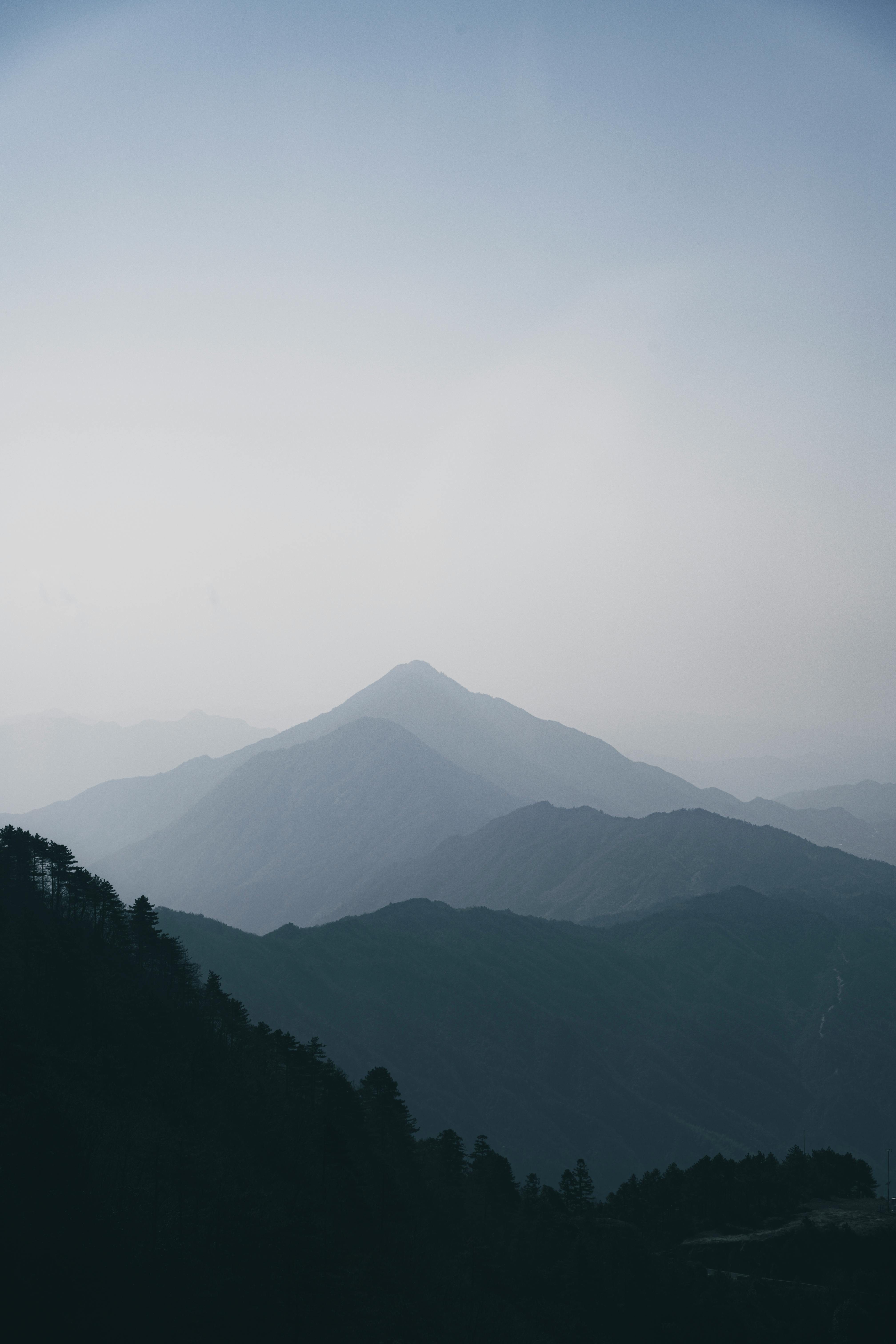 Free A peaceful view of misty mountains with layered peaks on a calm morning Stock Photo