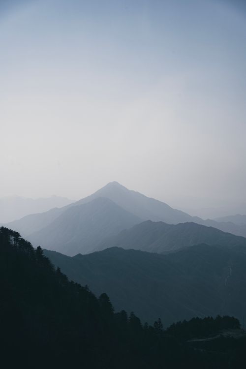 Free A peaceful view of misty mountains with layered peaks on a calm morning Stock Photo