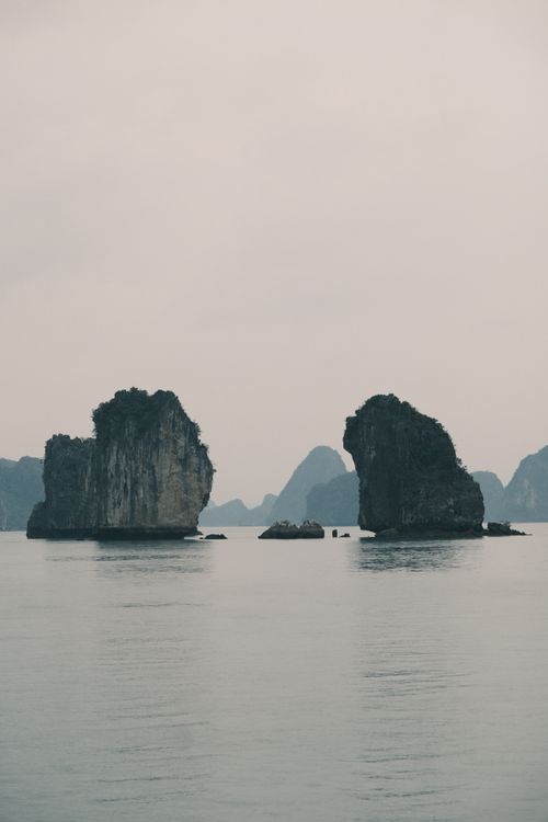 Free Tranquil morning scene of limestone karsts surrounded by calm waters in Halong Bay. Stock Photo