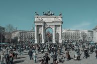 A bustling scene at Arco della Pace in Milan, capturing diverse people under a clear sky.