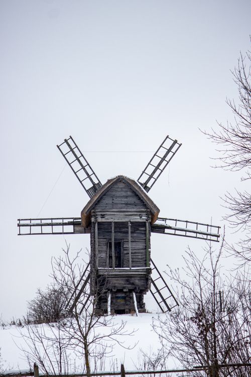 Free Charming old wooden windmill on a snowy hill, surrounded by winter trees. Stock Photo