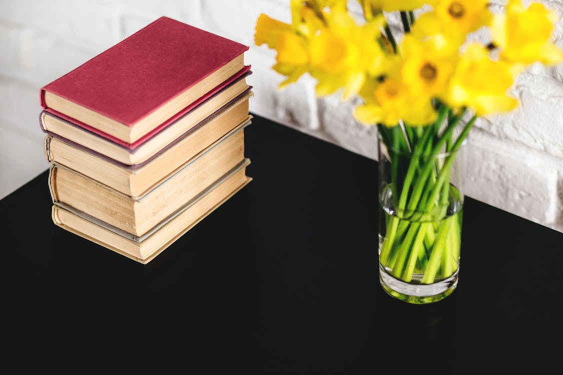 Hardbound Books Beside Yellow Petaled Flowers