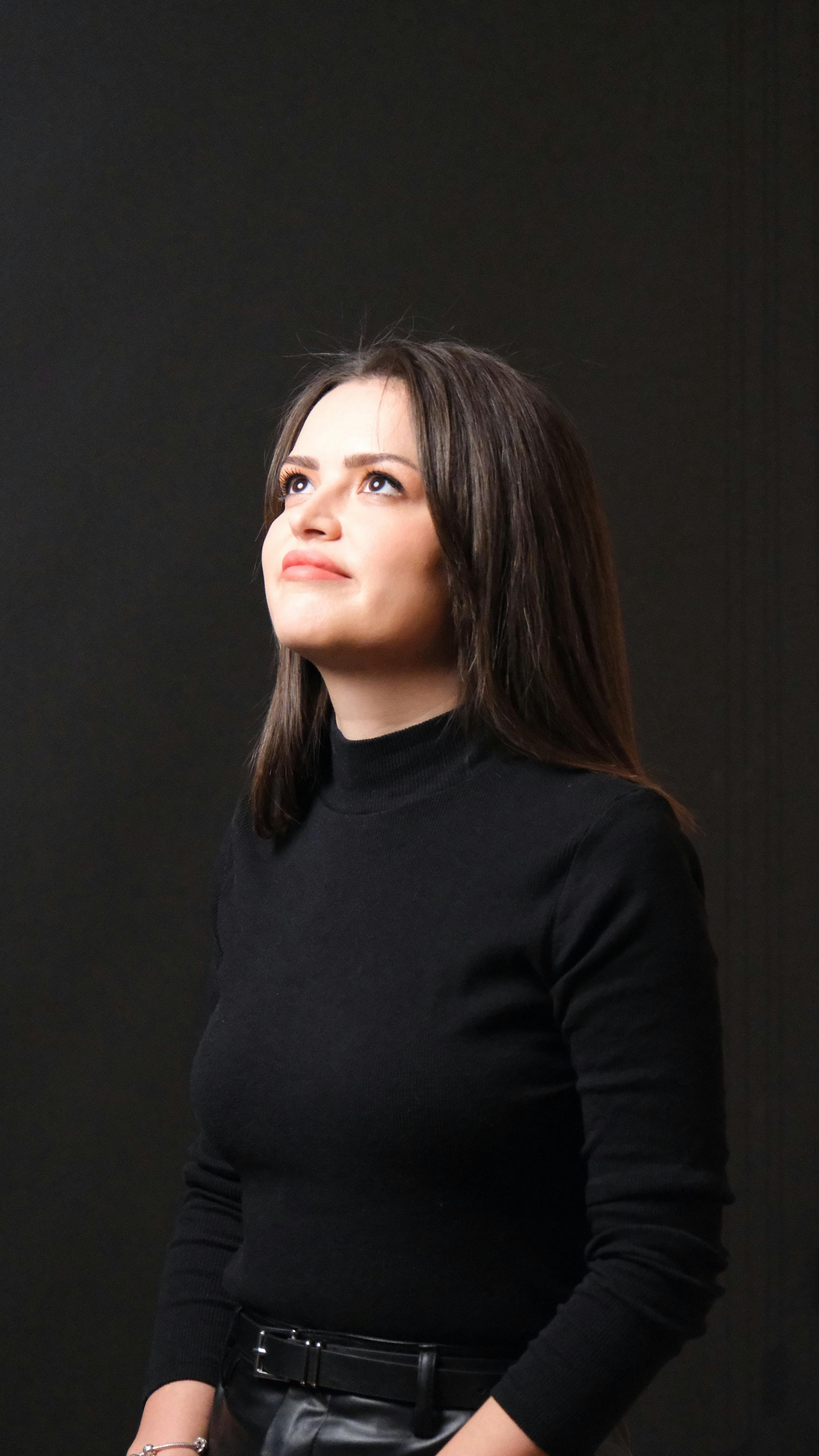 Gratis Ritratto di una donna che guarda verso l'alto con un'espressione pensierosa in un ambiente interno. Foto a disposizione