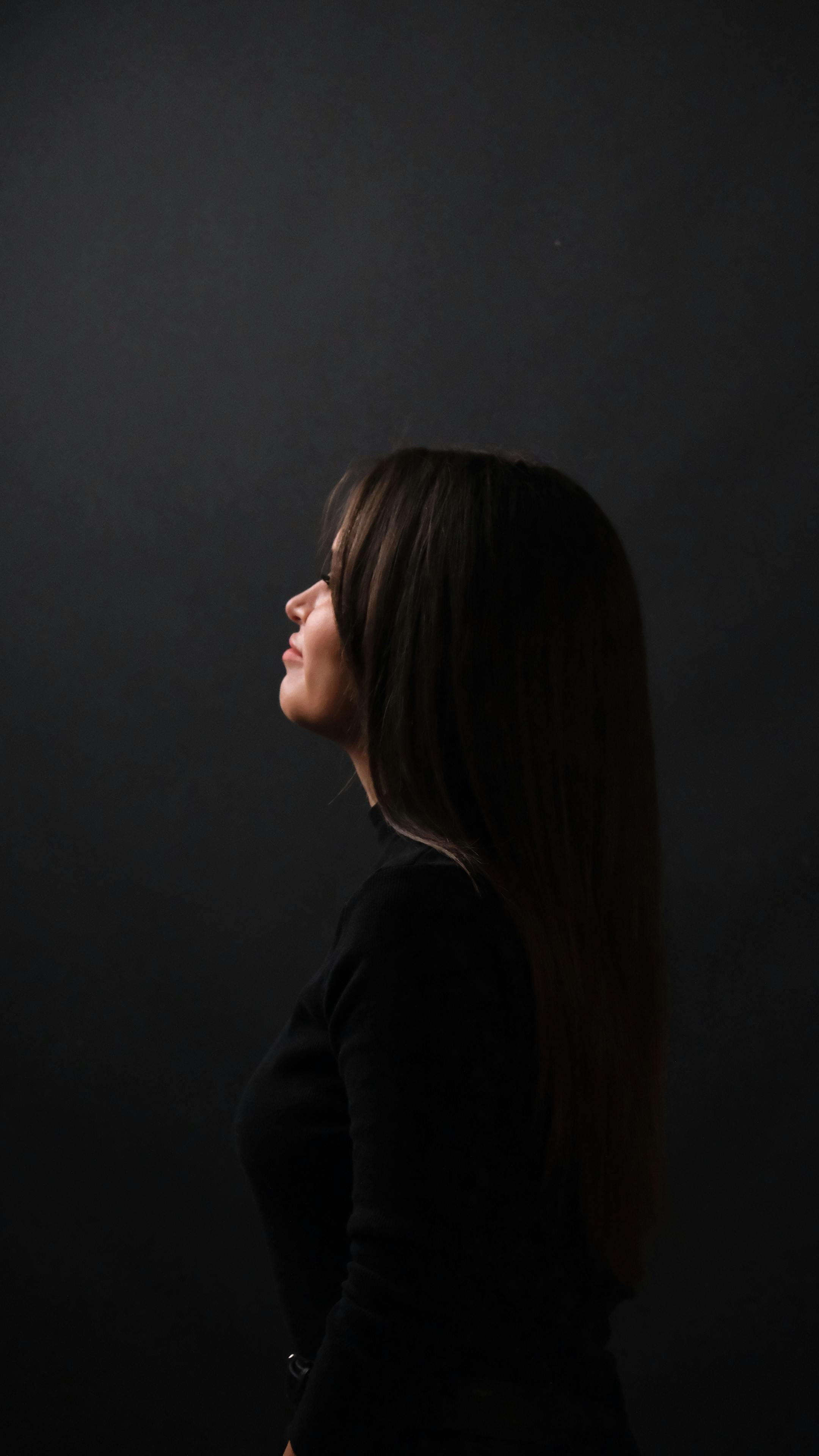Elegant profile portrait of a woman with long hair against a dark background.