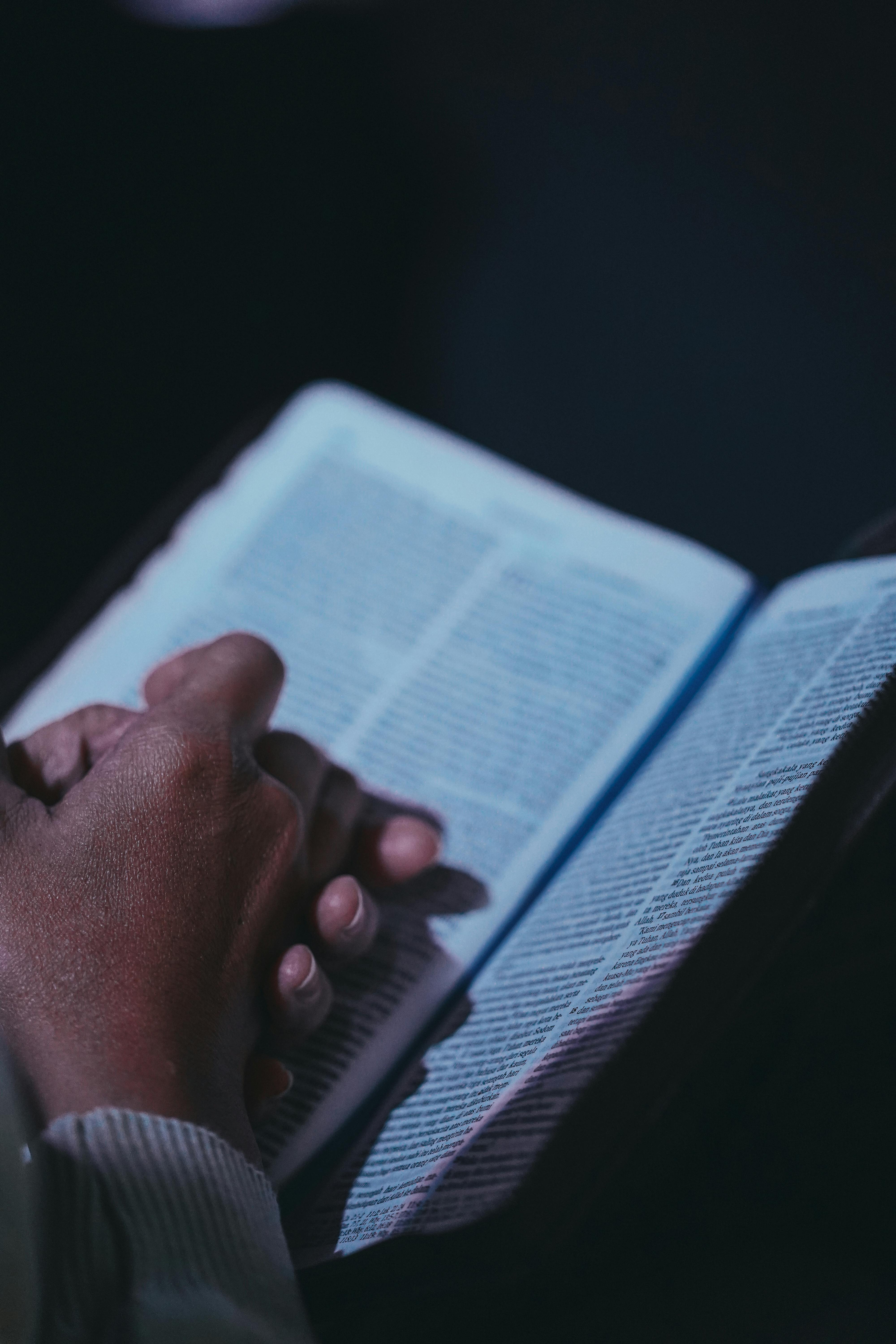ฟรี ภาพระยะใกล้ของมือที่กำลังถือหนังสือเปิดอยู่ สื่อถึงบรรยากาศที่สงบและครุ่นคิดอยู่ภายใน คลังภาพถ่าย
