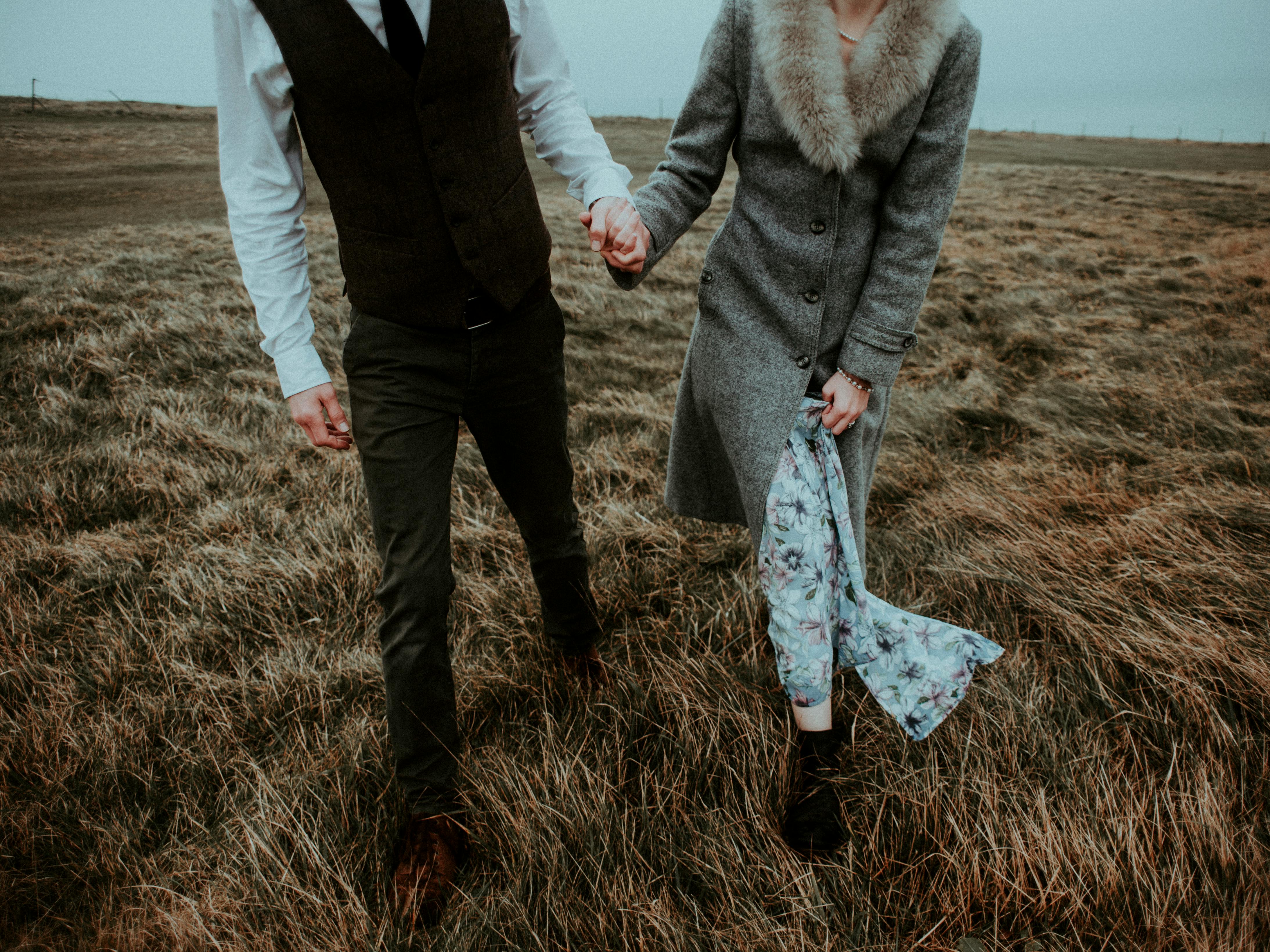 People holding hands while walking in a field. | Photo: Pexels 