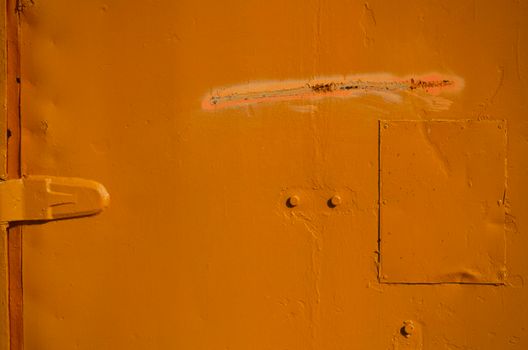 Detailed view of a textured rusty orange metal surface with bolts and door hinge.