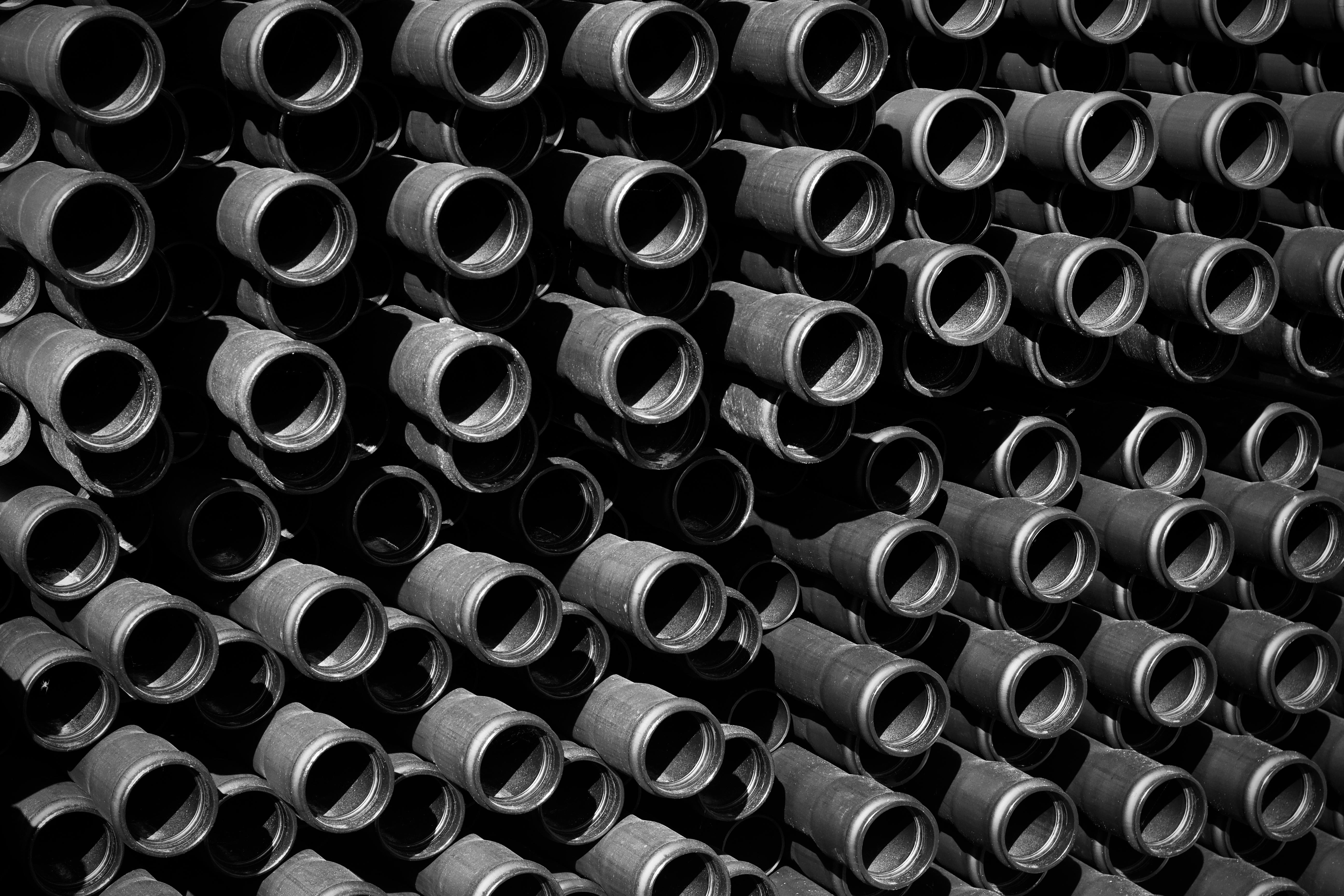 Gratuit Photo artistique en noir et blanc présentant un motif de tuyaux industriels formant une structure répétitive. Photos