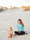 年轻女子和她的狗坐在海滩上，享受这宁静的自然时刻