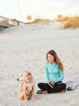 年轻女子和她的狗坐在海滩上，享受这宁静的自然时刻
