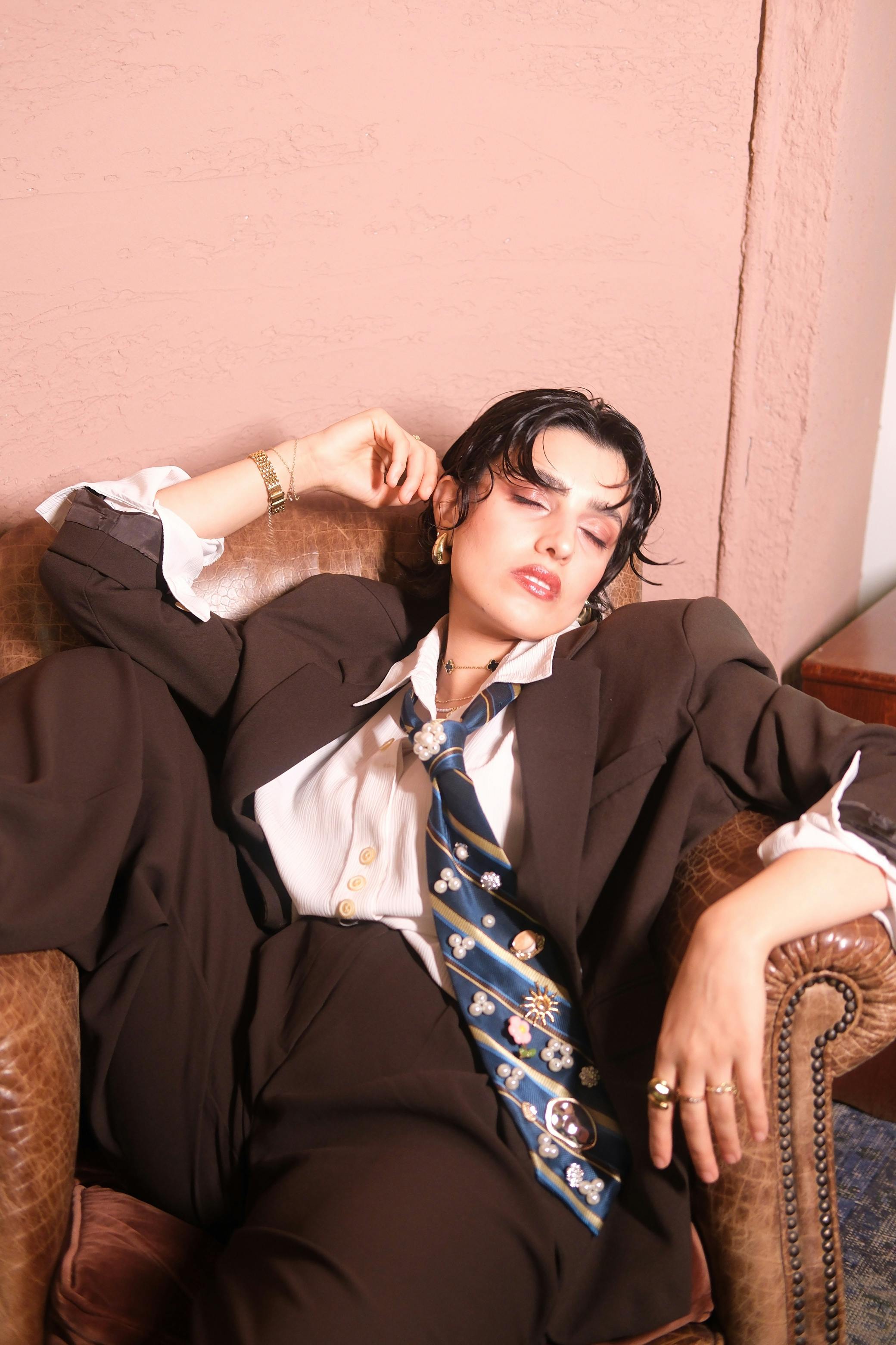 Free Fashionably dressed businesswoman relaxes in an oversized suit, exuding confidence and style. Stock Photo