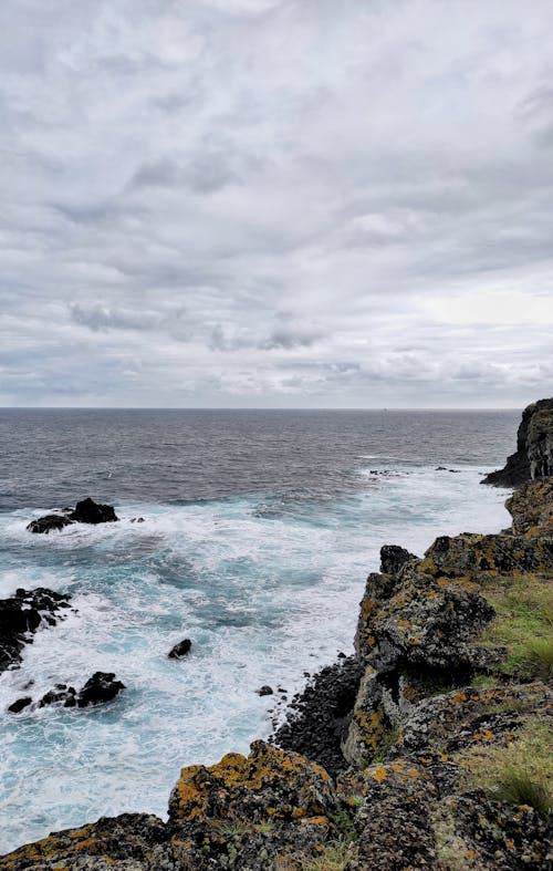 海浪猛沖在白雲下的岩石上