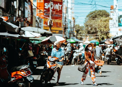 Vibrant outdoor market scene with people and scooters in Kon Tum, Vietnam.