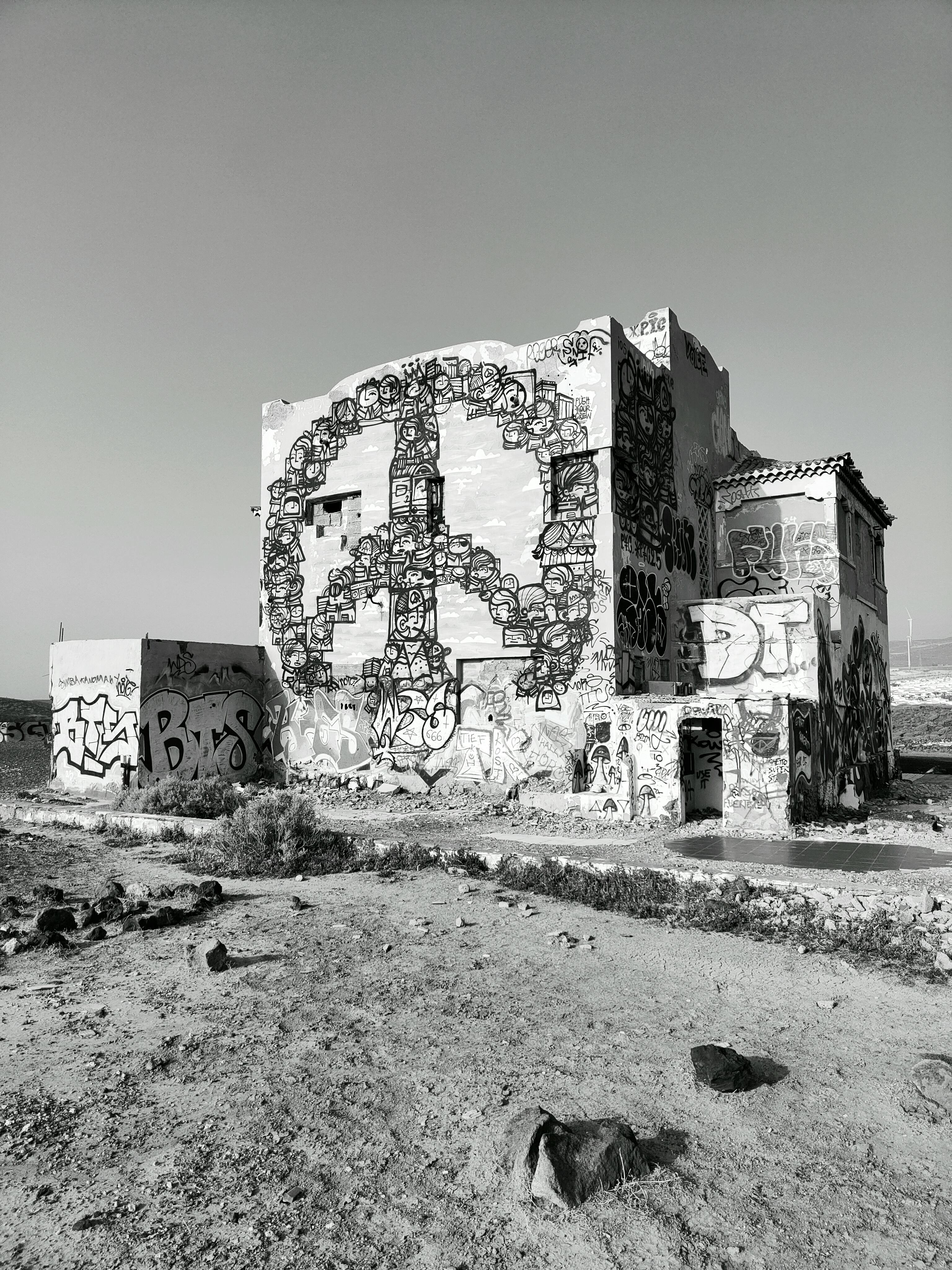 ingyenes Fekete-fehér kép egy graffitivel borított épületről sivatagi környezetben. Stockfotó