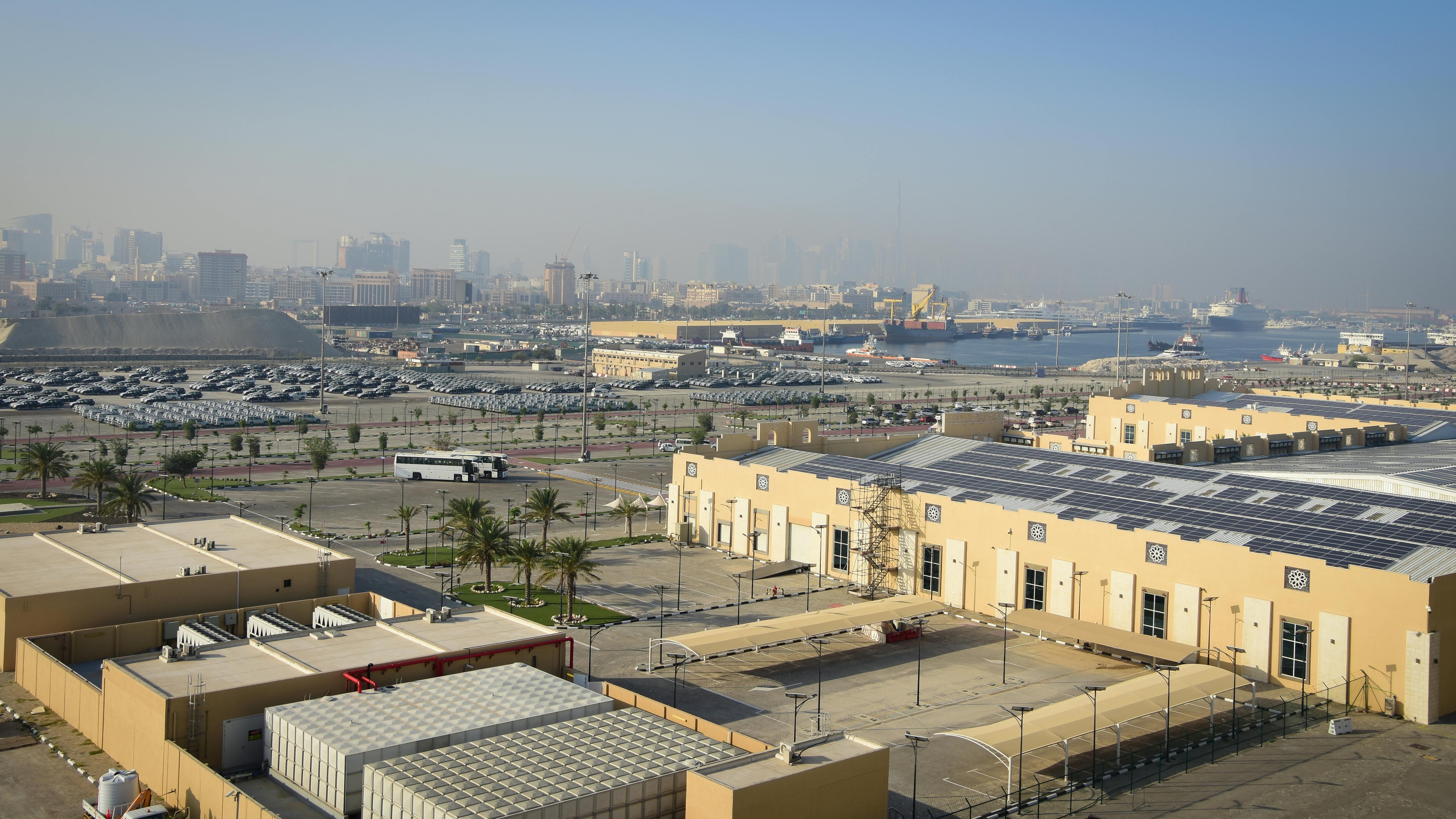 bezplatná Letecký pohled na dubajský přístav s průmyslovými budovami a vzdáleným panoramatem pod jasnou modrou oblohou. Základová fotografie