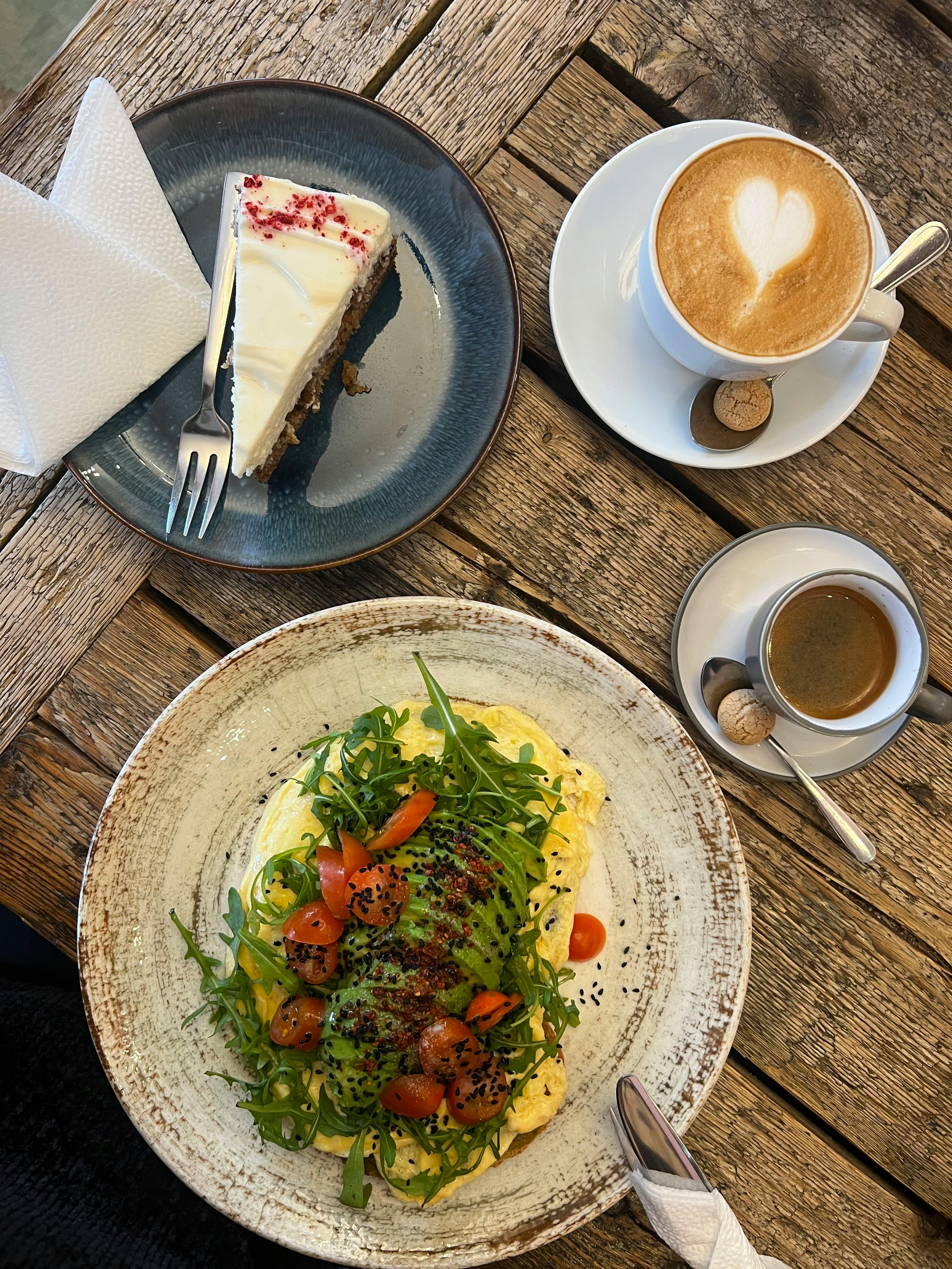 Enjoy a scrumptious breakfast with avocado toast, cheesecake, and coffee with latte art.