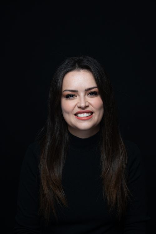 Free Studio portrait of a young woman smiling against a dark background, highlighting her natural beauty. Stock Photo