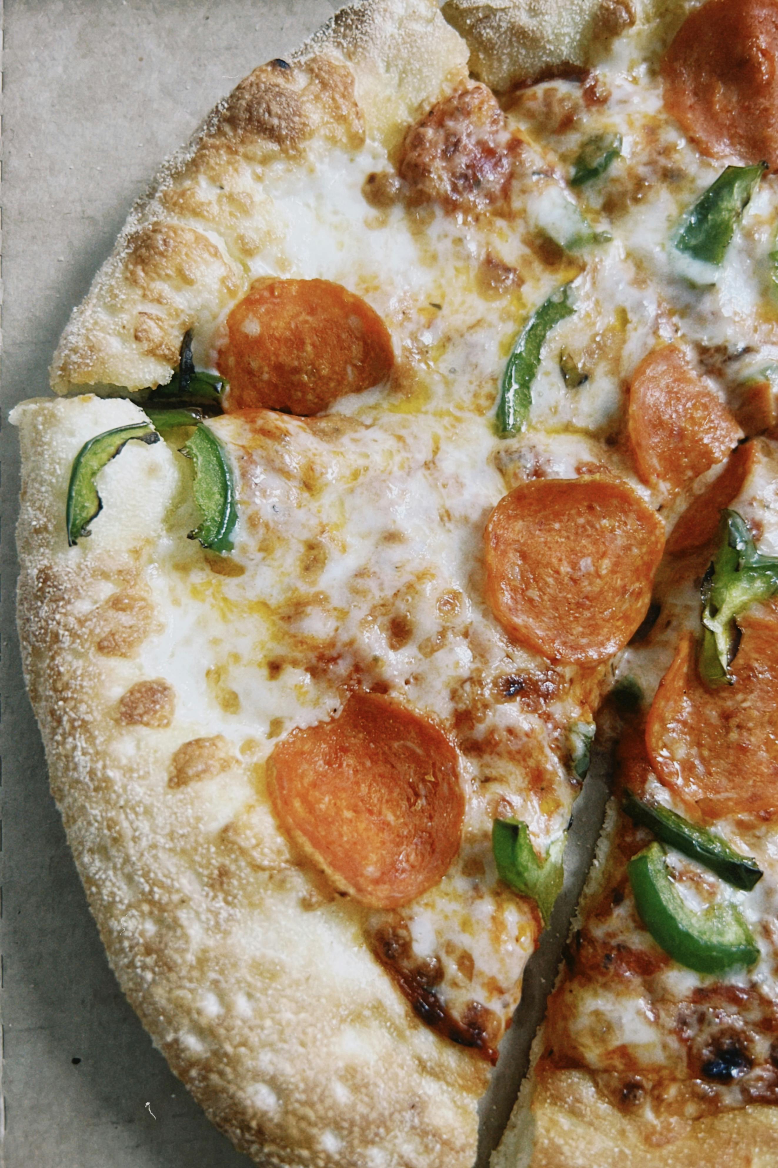 Ilmainen Herkullinen pepperonipizza sulatetulla juustolla ja vihreillä paprikoilla, täydellinen suolaiseen herkkuun. Kuvapankkikuva