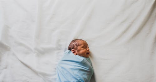 青い毛布で覆われた生まれたばかりの赤ちゃんの写真