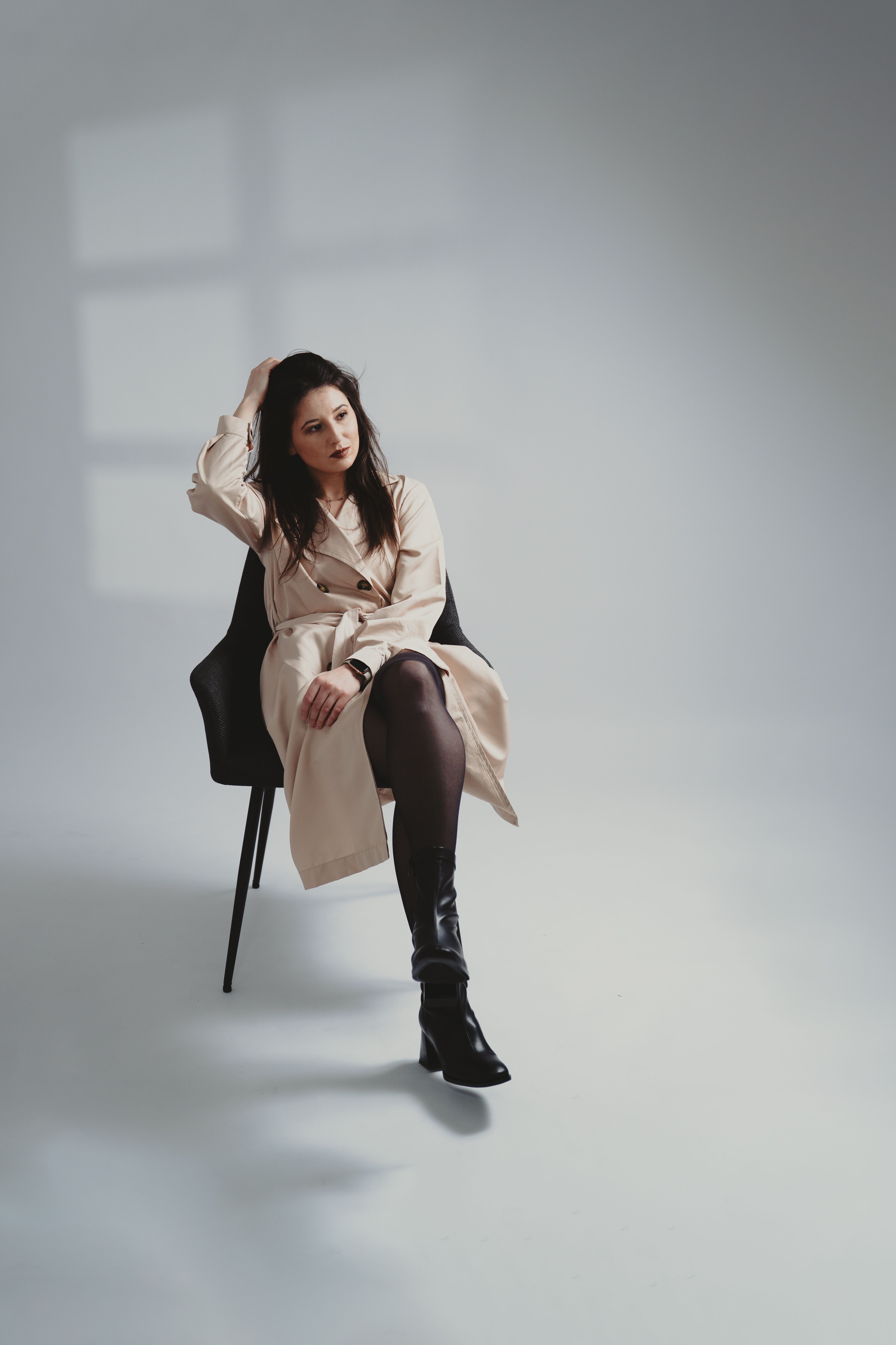 Elegant Woman in Trench Coat Sitting in Studio · Free Stock Photo