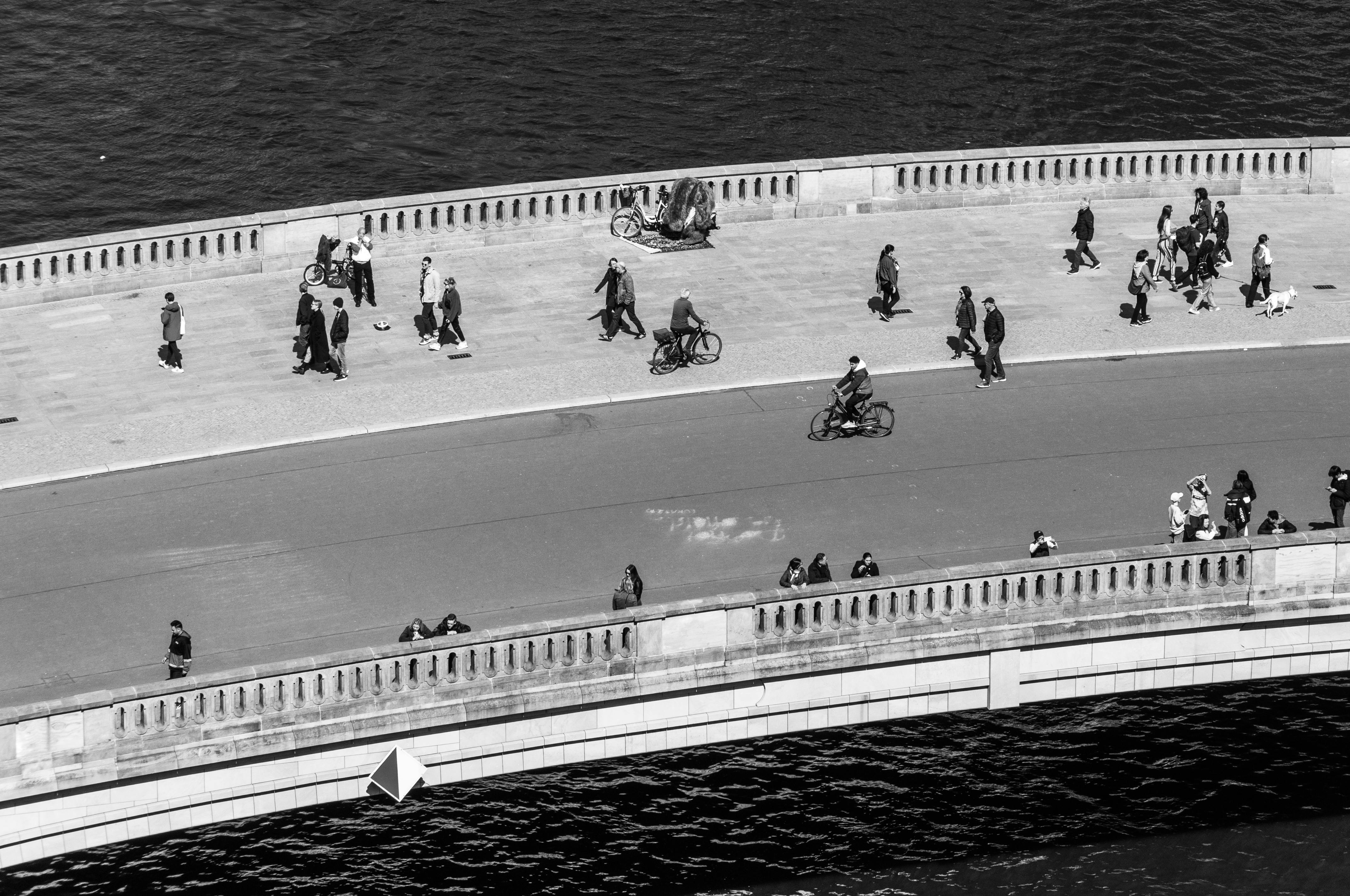 bezplatná Letecký pohled na lidi jdoucí a jedoucí na kole po mostě na černobílé fotografii, zachycující městský život. Základová fotografie