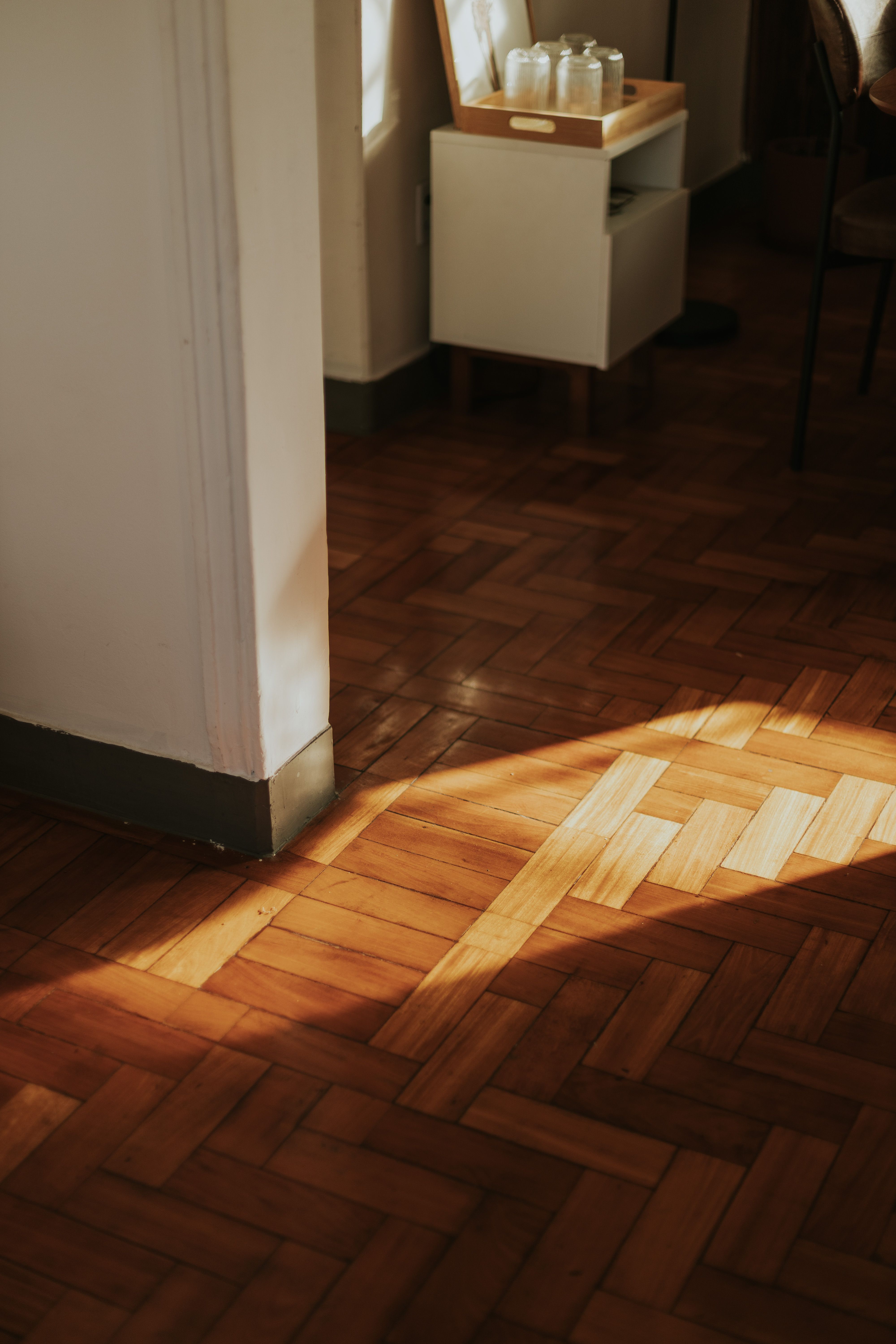 Fotomural La cálida luz del sol se proyecta sobre el suelo de parquet de madera en un acogedor ambiente interior.