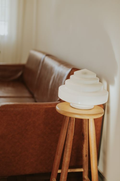 Free Minimalist living room with brown leather sofa and modern white lamp on wooden stool. Stock Photo