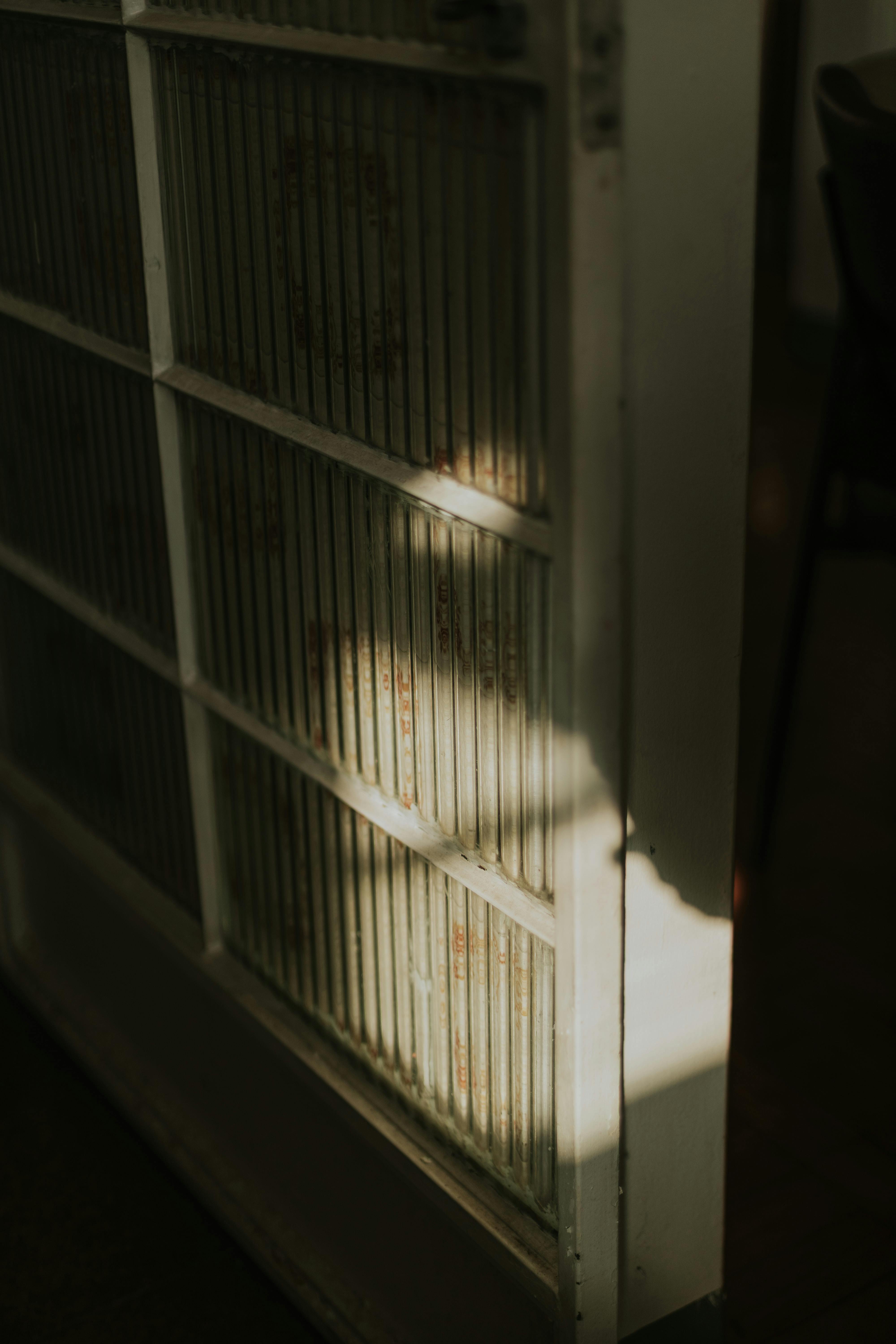 Gratuit Une ombre subtile se projette sur une porte ancienne, créant une atmosphère mystérieuse. Photos