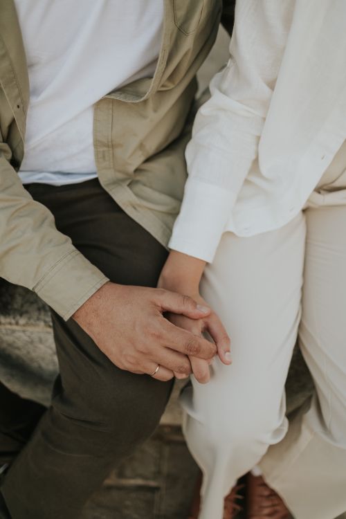 Free Close-up of a couple holding hands while sitting, a tender and intimate moment. Stock Photo