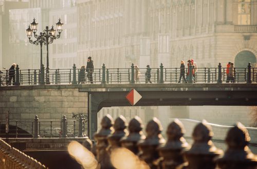Free A scenic view of people walking on a historical bridge in a European city with classic architecture. Stock Photo