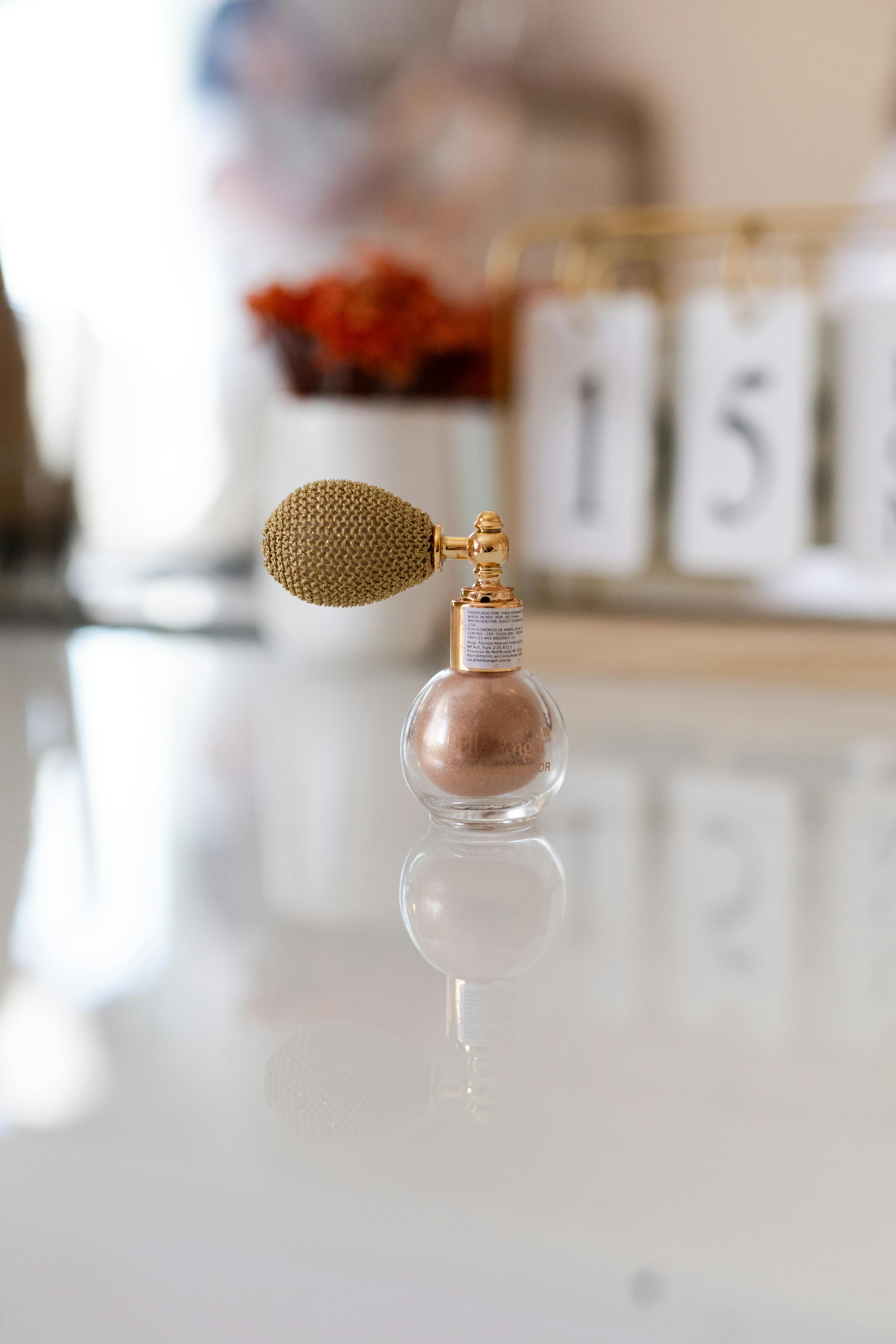 Gratis Un'elegante bottiglia di profumo vintage è adagiata con grazia su una superficie lucida, catturando lusso e stile. Foto a disposizione