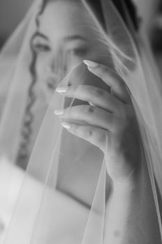 A beautiful bride delicately holds her veil, embodying grace and elegance.