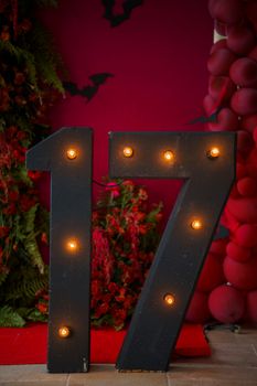 Glowing number 17 on a vibrant red background with festive decor and bats.