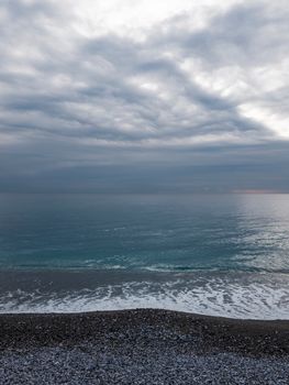 A tranquil coastal landscape with dramatic clouds over the ocean, depicting nature's calm and turbulence.